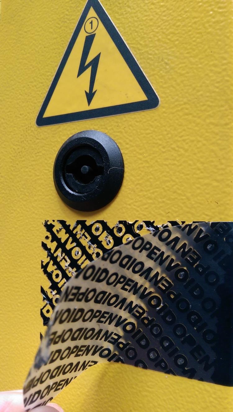 Black tamper-evident void label on a yellow electrical equipment box