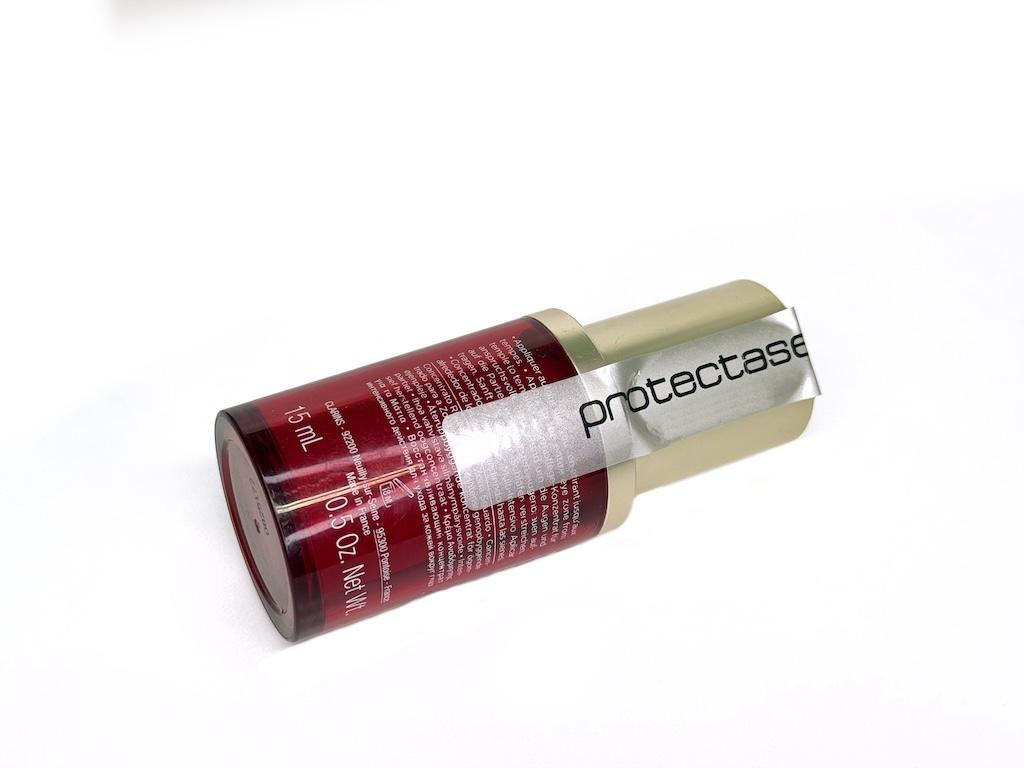 Red luxury bottle with tamper-evident silver brand protection label applied to cap seal