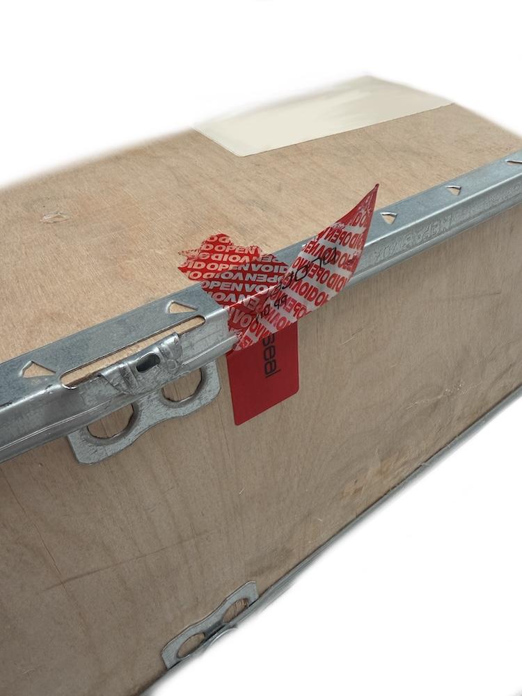 Red tamper-evident security label applied to a shipping crate