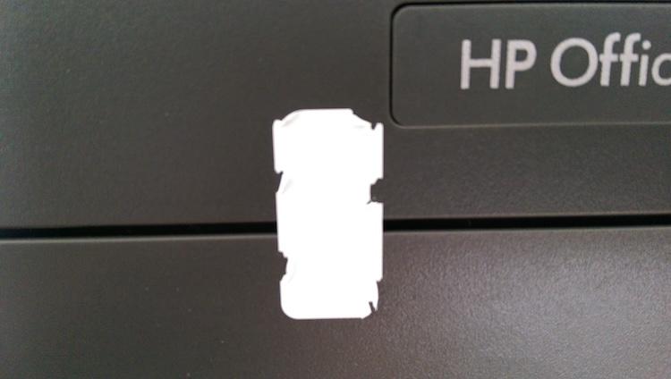 White tamper-evident void label applied to an HP office printer asset